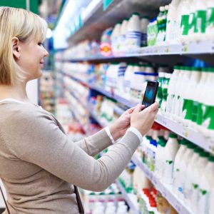 Woman photographing with smartphone label of dairy products in shop